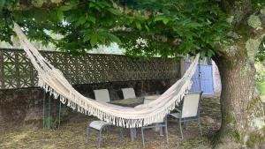 a hammock with chairs and a table under a tree at Casa Camiño do Eume in A Coruña +33 photos