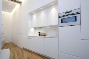 Una cocina blanca con gabinetes blancos y un microondas. en Genteel Home Castilla IV, en Sevilla