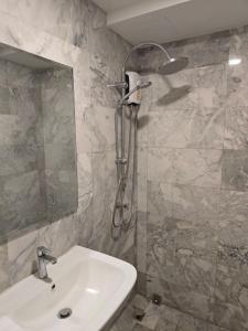 ein Badezimmer mit Waschbecken und Dusche mit Spiegel in der Unterkunft 777 Beach Condotel in Mai Khao Beach