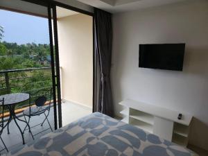 Schlafzimmer mit einem Bett und einem Balkon mit einem TV in der Unterkunft 777 Beach Condotel in Mai Khao Beach