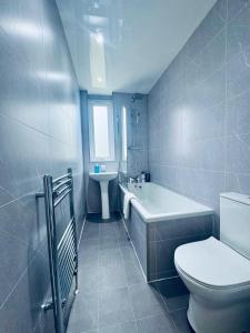 a bathroom with a toilet and a tub and a sink at Modern 2 Bedroom with extra Loft Bedroom in Glasgow
