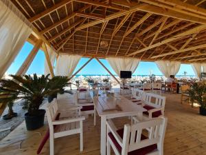a restaurant with white tables and white chairs at Residence Sole 5 by Wave - Apartament luxury 60mp cu terasa si vedere la mare, acces direct pe plaja OhiOhi Beach- Mamaia Nord - Restaurant, Parcare gratuita in Mamaia Sat/Năvodari