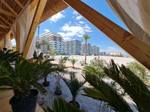 a view of a beach with palm trees and buildings at Residence Sole 5 by Wave - Apartament luxury 60mp cu terasa si vedere la mare, acces direct pe plaja OhiOhi Beach- Mamaia Nord - Restaurant, Parcare gratuita in Mamaia Sat/Năvodari