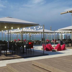 a patio with tables and chairs and lights and the ocean at Key to Jurmala in Jūrmala