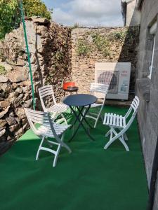 a patio with a table and chairs on a green floor at Rosalie's House in Pommerit-Jaudy
