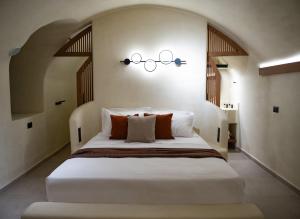 una camera da letto con un grande letto bianco con un lampadario di Iama Luxury Suite Santorini a Imerovigli Altre 9 foto