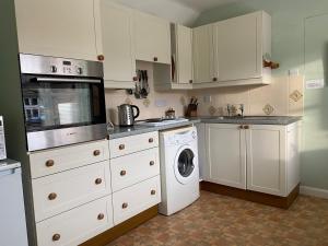 a kitchen with white cabinets and a washing machine at Little Furrows, Wenhaston in Wenhaston