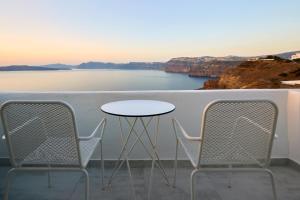 un tavolo e sedie su un balcone con vista sull'acqua di Santorini View ad Akrotírion Altre 37 foto