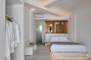 a white bedroom with a bed and a mirror at Santorini View in Akrotiri