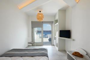 a bedroom with a bed and a tv and a balcony at Santorini View in Akrotiri