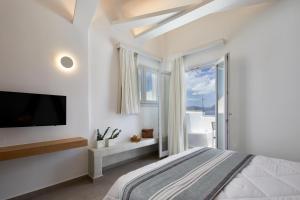 a white bedroom with a large bed and a tv at Santorini View in Akrotiri