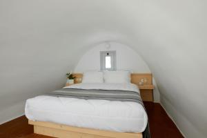 a bedroom with a white bed with a window at Santorini View in Akrotiri