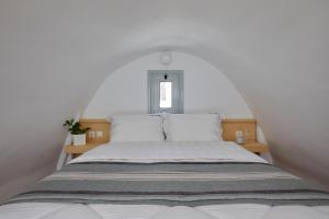 a white bedroom with a large bed with white walls at Santorini View in Akrotiri