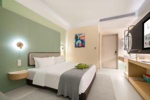 a bedroom with a bed with a green stuffed animal on it at Layflat Hotel in Shenzhen