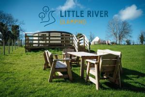 巴利马尼Little River Glamping的一张木桌和椅子坐在田野里