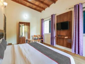 una camera da letto con un letto grande e una TV a schermo piatto di The Mountain Lodge Manali !! Scenic Mountain View ! Parking ! Restaurant ! Tasty Food ! Preferred Property a Manāli