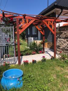 a wooden pergola with a blue bucket in the grass at Ulita in Bumbeşti-Jiu