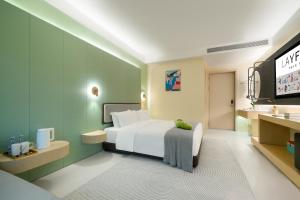 a bedroom with a white bed and a television at Layflat Hotel in Shenzhen