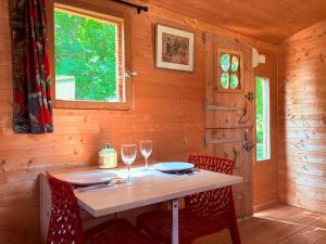 ein Tisch in einer Holzhütte mit Weingläsern in der Unterkunft La Roulotte de l'Hermitage in Ambonil + 12 Fotos