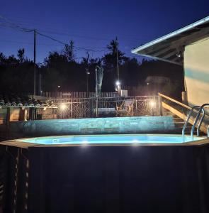 a swimming pool at night with lights at Guest House Kandaferi 2 in Elena