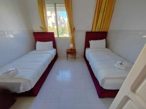 Stylish Coastal Stay with Panoramic Sea Views في طنجة: سريرين يجلسون في غرفة مع نوافذ