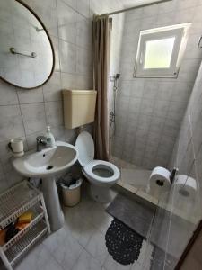 Un baño con inodoro, lavabo y espejo. en Milica Soba sa kupatilom 2, en Petrovac na Moru
