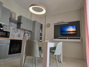 a kitchen with a table with chairs and a tv on the wall at Nido Salento Gallipoli in Gallipoli