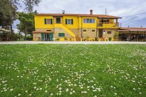 a yellow house with a field of flowers in front of it at B&B Centro Ippico Andrea in Porto Recanati