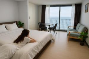 a woman laying on a bed in a hotel room at Yeosu U-Bless Terrace Ocean View in Yeosu
