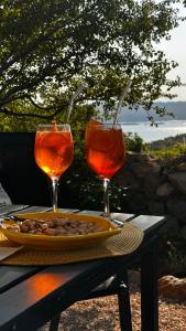 two wine glasses and a plate of food on a table at Kuća za odmor Velebit by the sea in Stinica