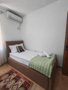 a small bedroom with a bed with a green blanket at Vangert Apartment in Berat