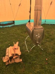 un nichoir posé sur l'herbe à côté d'un poêle dans l'établissement Natur pur im Tipi -Dein Rückzugsort in Schwedens Wildnis, à Arvika