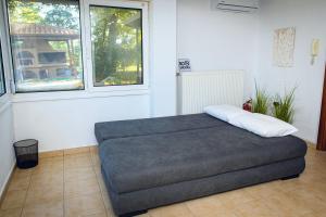 a bed sitting in a room with two windows at Thalassa Luxury Apartments - Korinos in Skála Korinoú