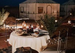 a table with food on it in front of a building at Sahara horizon Camp in Merzouga