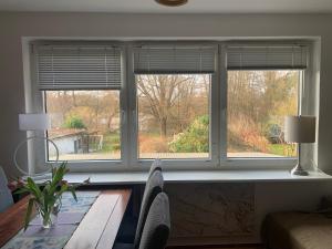a living room with three windows and a table at Charmante Doppelhaushälfte Am Schwanensee 4 in Plön