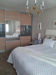 a bedroom with a large white bed and a chandelier at Habitación en casa moderna con jardín in Santa Cruz de Bezana