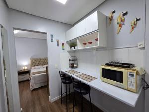 a kitchen with a counter with a microwave and a bed at Loft Arara Manaus in Manaus