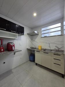 a kitchen with white walls and counters and a sink at Loft Arara Manaus in Manaus +3 photos