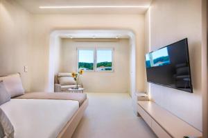 a white room with a bed and a flat screen tv at Cocoοns Suites & Villas Fourka in Fourka