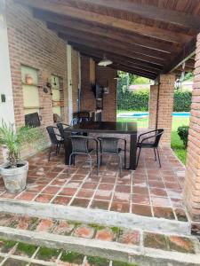 eine Terrasse mit einem Tisch und Stühlen auf einer Backsteinterrasse in der Unterkunft Casa con quincho y pileta in Cordoba