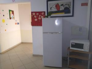 a white refrigerator in a room with a microwave at Melaya Budget Hostel in Faro