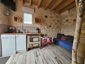 a kitchen and living room with a blue couch in a room at La cabane de Normandie in Nonant