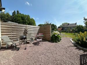 a patio with chairs and a table and a fence at La cabane de Normandie in Nonant