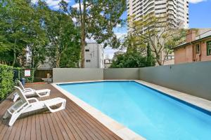 a swimming pool with two lounge chairs on a wooden deck at Spacious apartment with stunning harbour view in Sydney