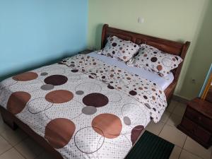 un letto con piumone e cuscini bianchi e marroni di GRÂCES hôtel a Yaoundé