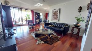 a living room with a black couch and a glass table at Spacious apartment with stunning harbour view in Sydney
