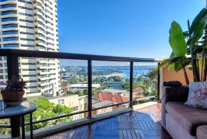 a balcony with a couch and a view of a city at Spacious apartment with stunning harbour view in Sydney