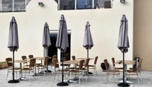 un grupo de sombrillas grises, mesas y sillas en Hotel Bleu Azur, en Argelès-sur-Mer