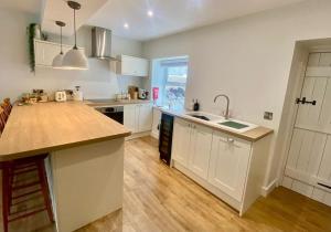 a kitchen with white cabinets and a wooden counter top at Morfarch traditional stone cottage within Conwy walls in Conwy +31 photos