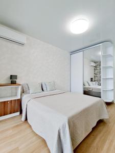a white bedroom with a large bed and a mirror at Радужная студия Вокзал Харьков-Пассажирский in Kharkiv +36 photos